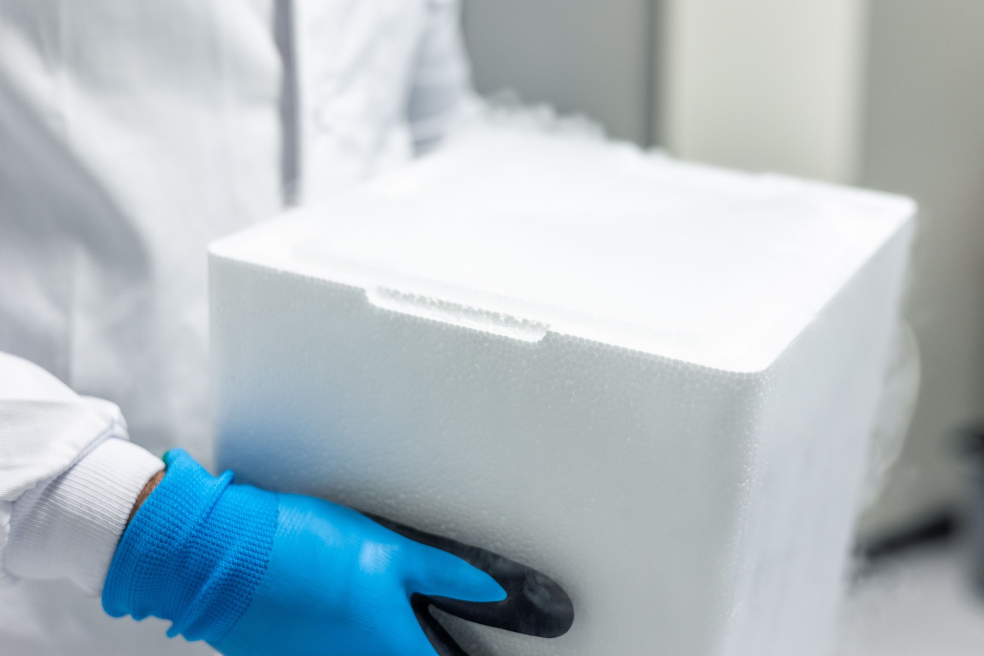 Scientist carrying a styrofoam box with dry ice in laboratory